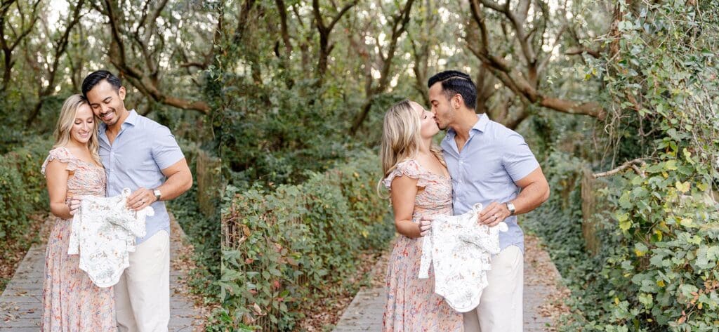 Couple portraits holding baby onesie by the trees