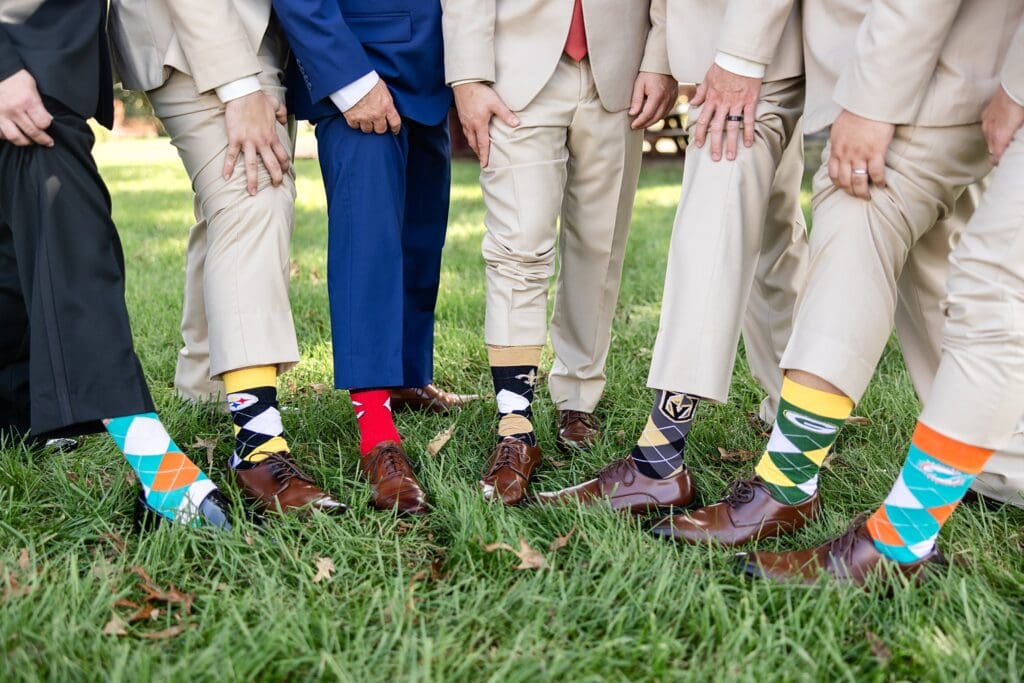 Groomsmen showing off football themed socks with suits