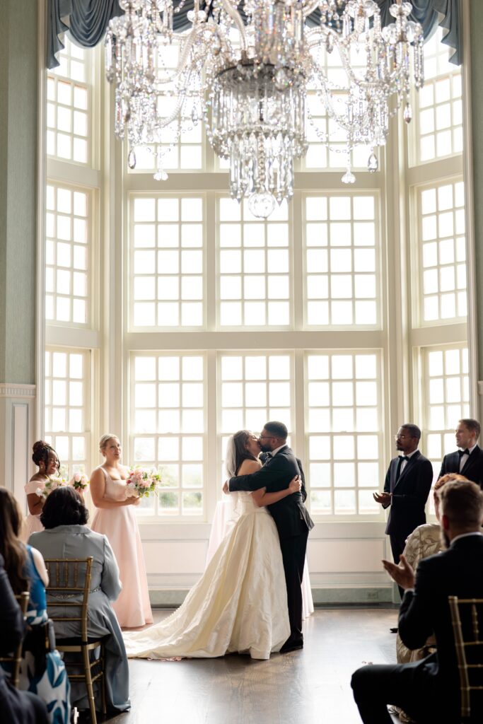Bride and groom kissing surrounded by guests