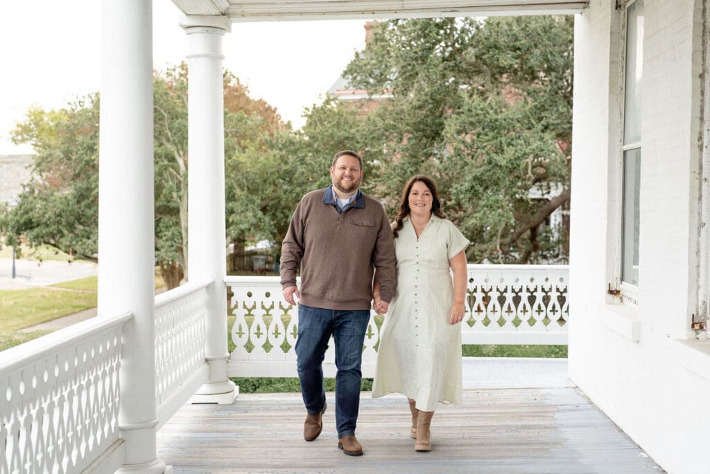 Couple holding hands and smiling at camera for engagement photos
