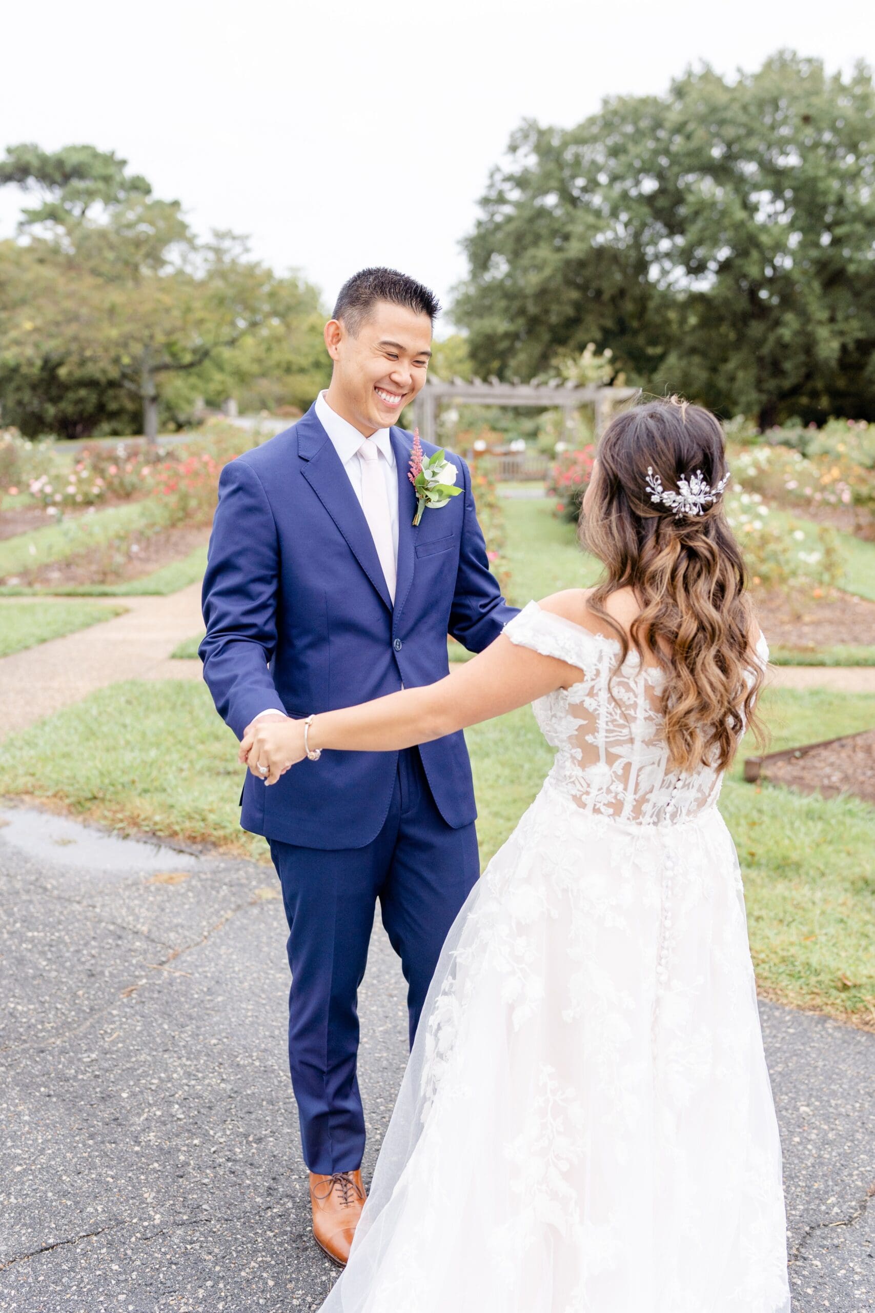 Groom smiling at bride surrounded by flowers at Norfolk Botanical Garden