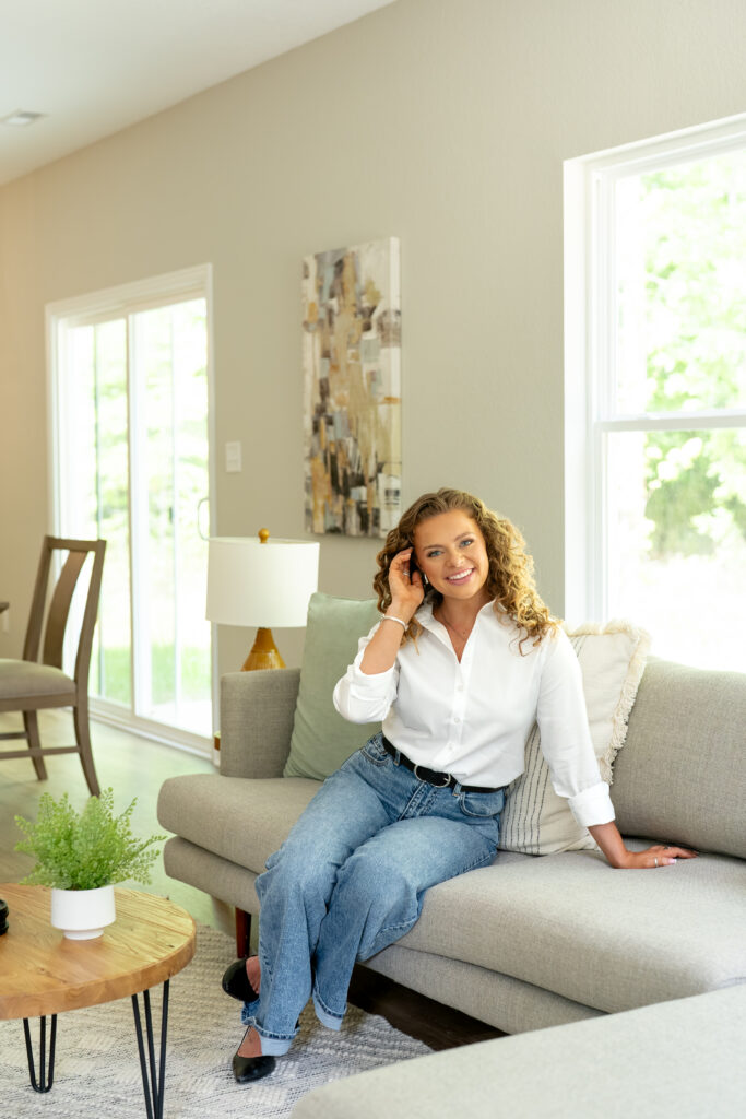 realtor sitting on couch smiling at camera for branding photoshoot