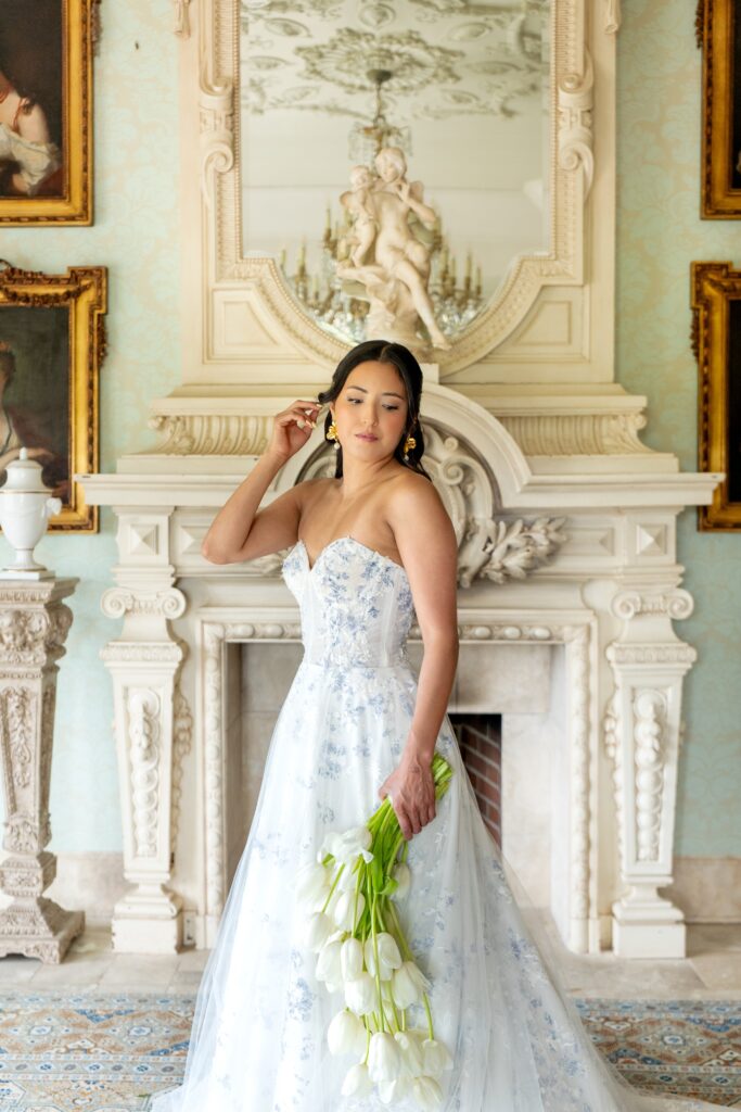 Bride holding flowers in front of fireplace